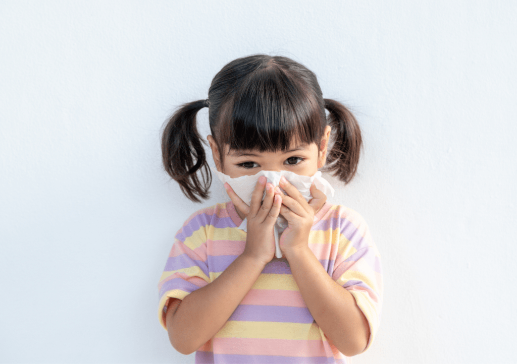 little girl with pigtails blows her nose