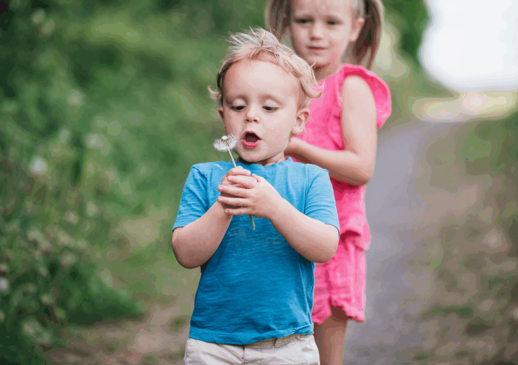Young boy blowing a dandelion outdoors in Texas during spring, a common trigger for spring breathing issues in Texas among children.