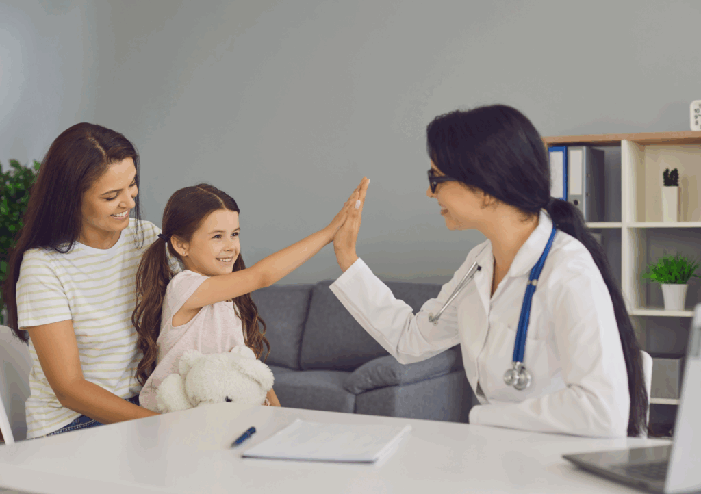 Smiling child high-fives a pediatric doctor during a spring health checkup, showing care for spring breathing issues in Texas families.