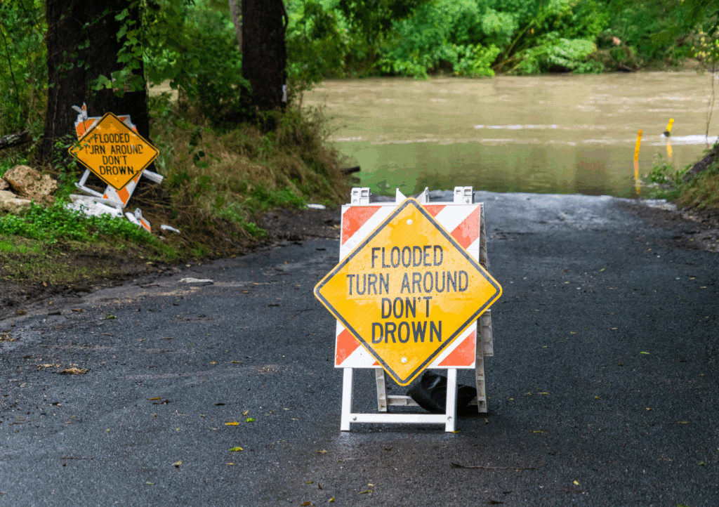 Flooded road with “Turn Around Don’t Drown” warning sign blocking the way