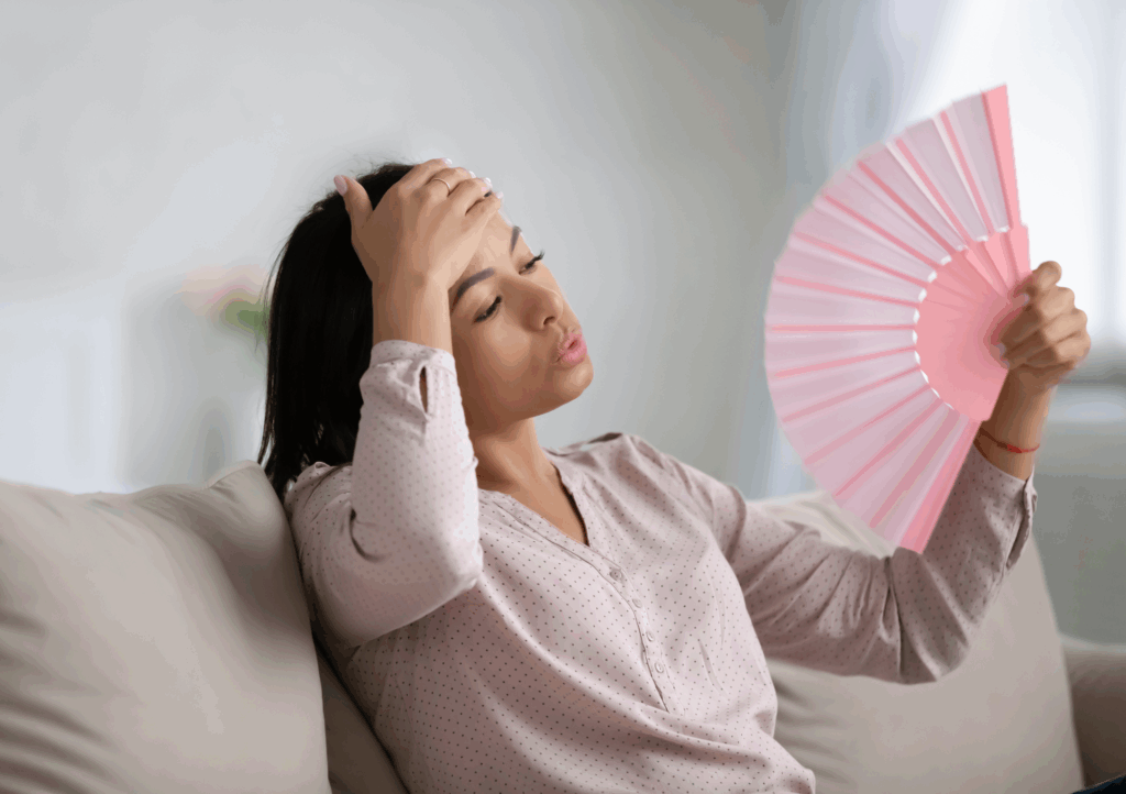 Woman fanning herself on couch, showing signs of heat exhaustion after power outage