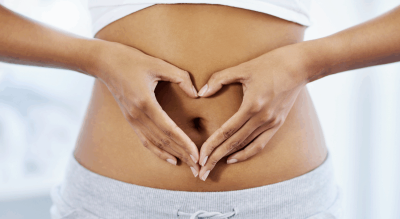 Person forming a heart shape with hands over their stomach, symbolizing gut health and wellness.