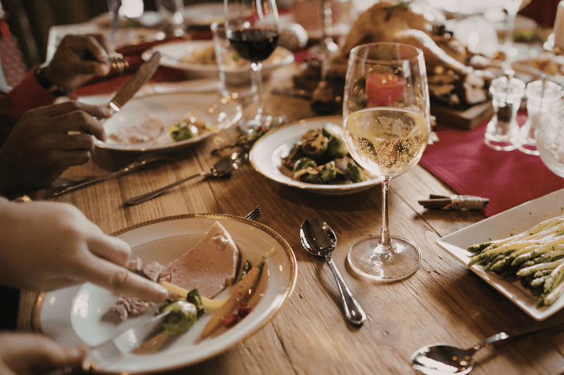 Holiday meal setting with shared dishes and wine, representing rich seasonal foods that may affect digestion.